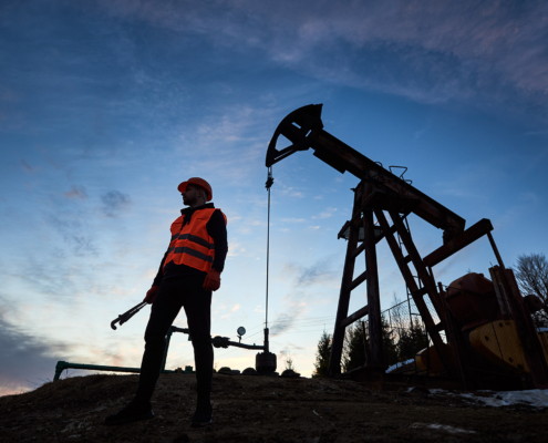 Silhouette Of An Oilman In Orange Vest And Helmet