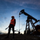 Silhouette Of An Oilman In Orange Vest And Helmet